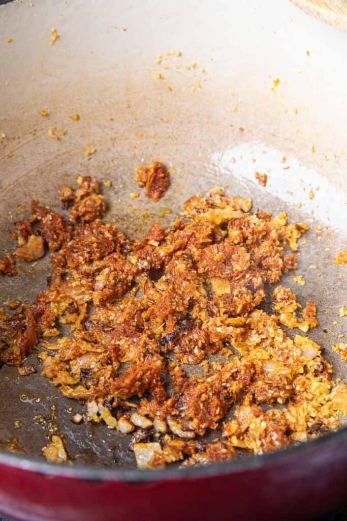 Sautéed red curry paste in a pot.