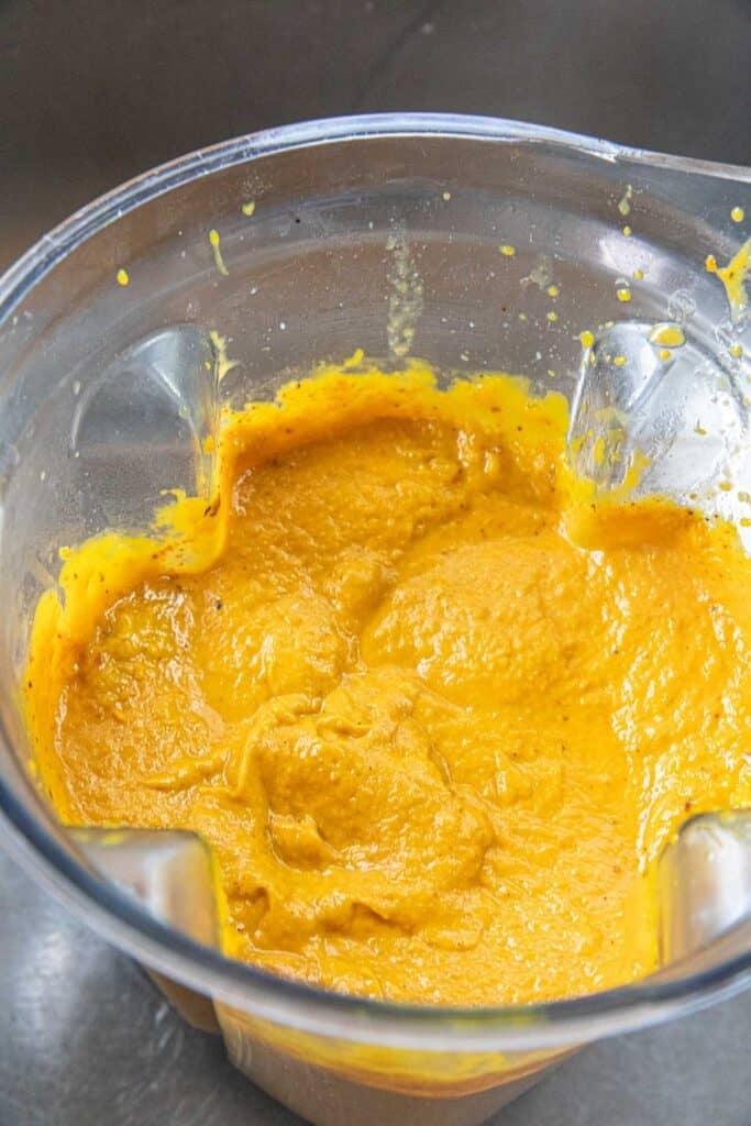 Orange pumpkin puree for a Thai curry recipe in a blender.