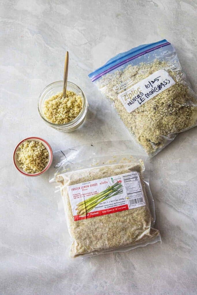 Minced lemongrass in a plastic bag, in a ziplock bag, in a small bowl and some in a glass jar with a spoon. 