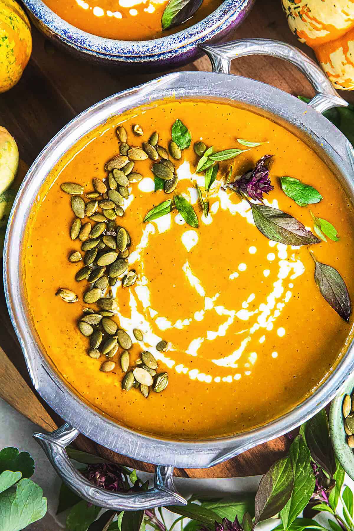 A bowl of creamy Thai pumpkin curry recipe on a table with basil leaves around. 