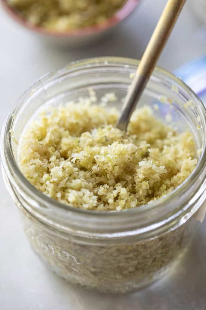 Minced lemongrass in a glass jar with a spoon. 
