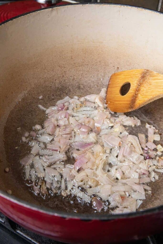 Sautéed shallots in a pot with a spatula, stirring. 