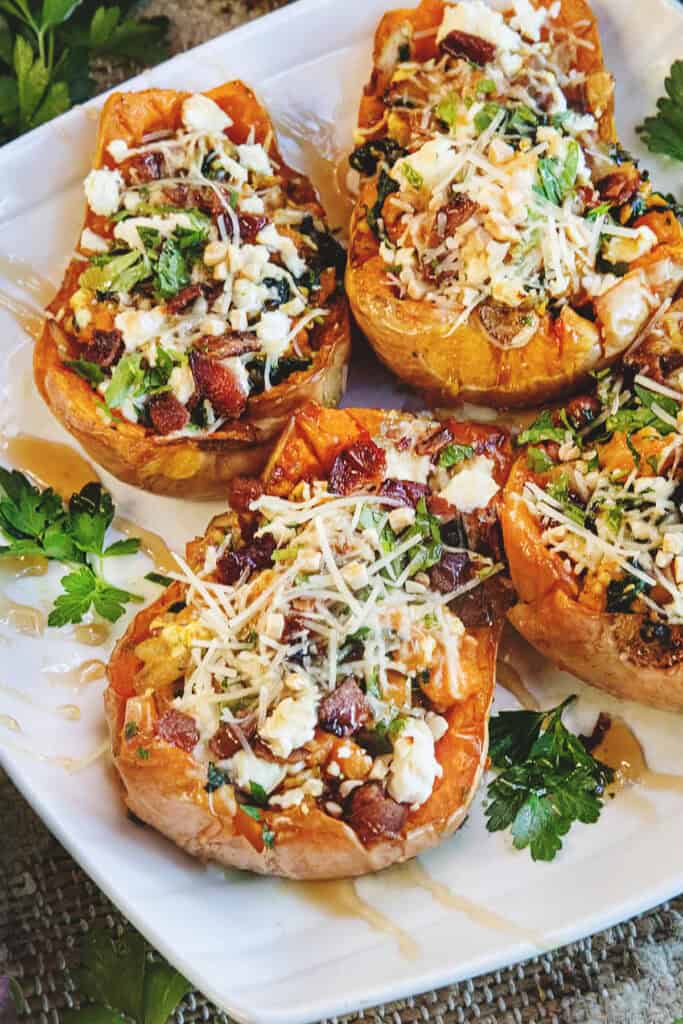 Thai-inspired baked butternut squash halves with feta and herb garnish on a serving dish.