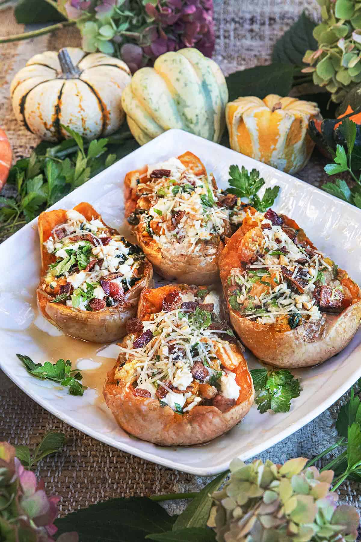 Golden roasted butternut squash stuffed with feta, spinach, and peanuts, served with fresh herbs.
