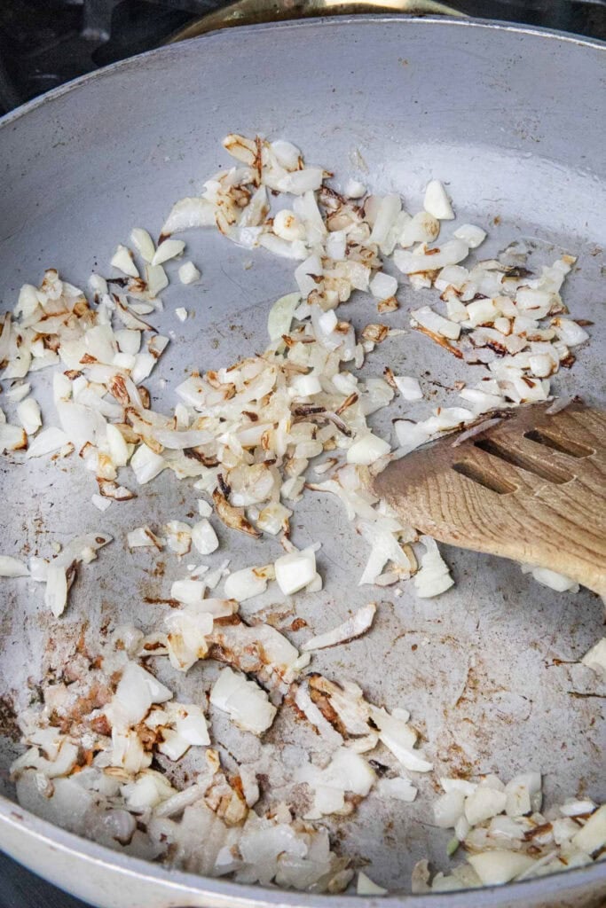 Sautéed garlic and onion in a pan with a spatula. 