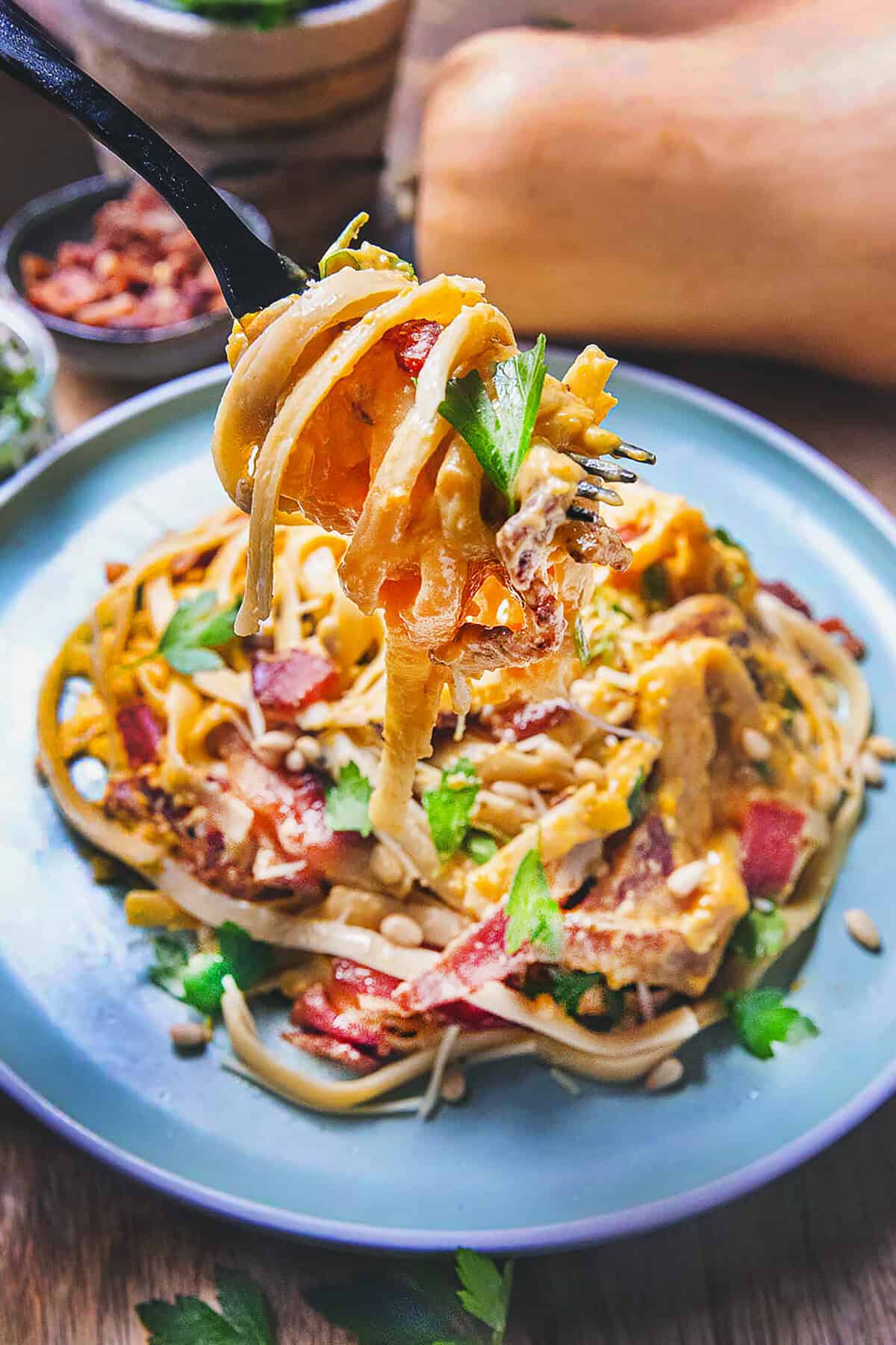 A fork lifting Creamy butternut squash fettucine pasta on a plate on the table. 