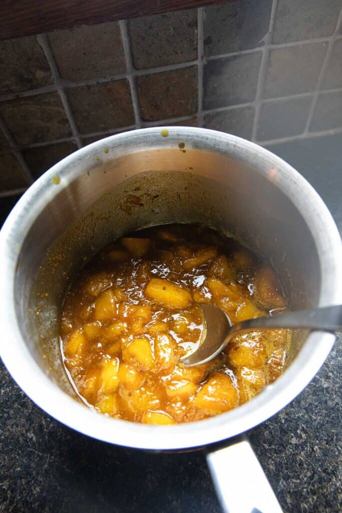 Cooked yellow mixture for mango curry sauce in a pot.