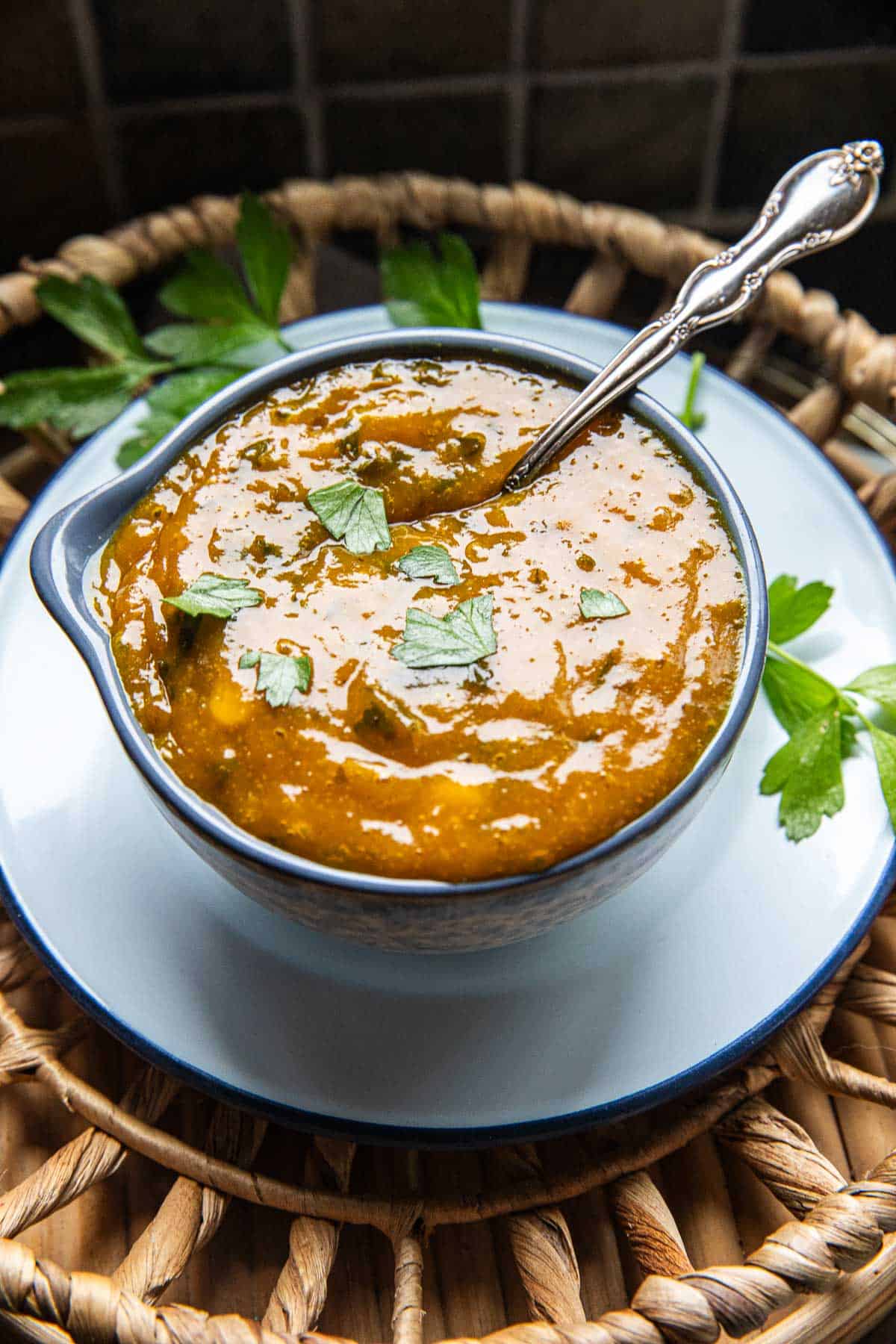 A spoon dipped in mango curry dipping sauce from a bowl. 