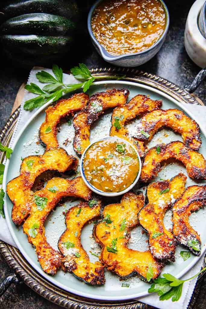 Roasted Acorn squash slices on a plate with a mango curry sauce in the middle.