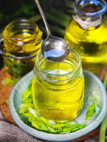 a spoon lifting scallion oil from a glass jar.