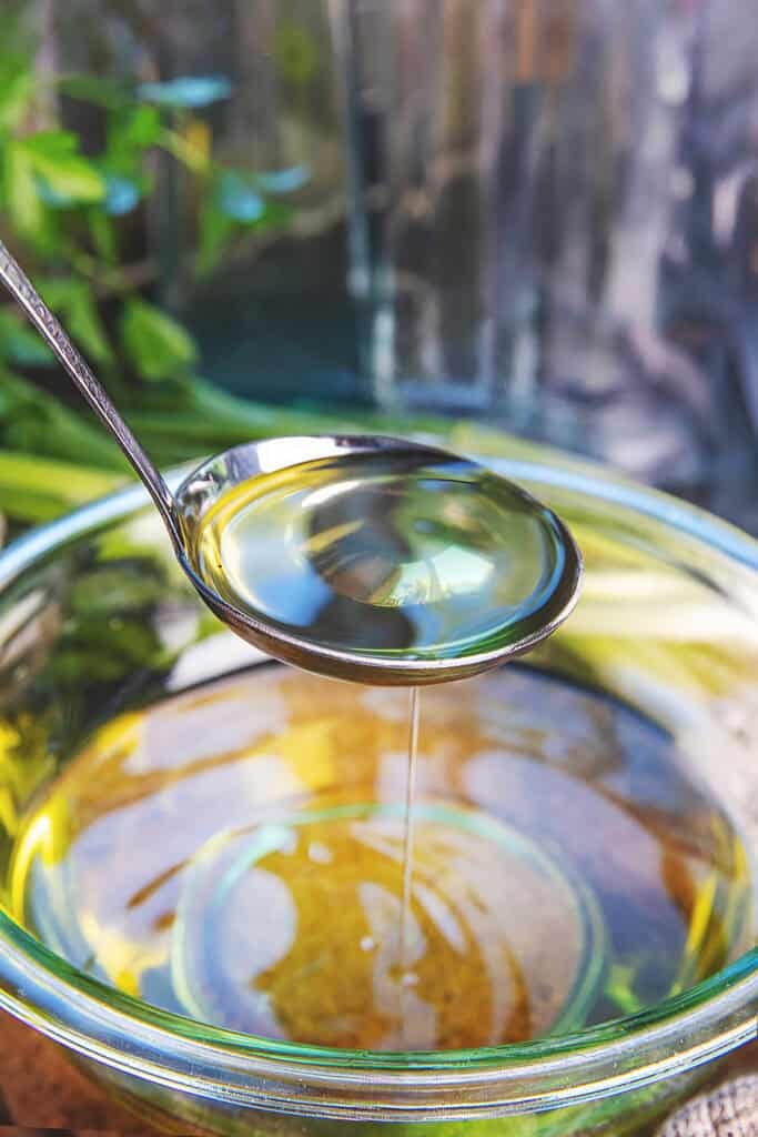 A ladle lifting mỡ hành or scallion oil from a bowl of oil. 