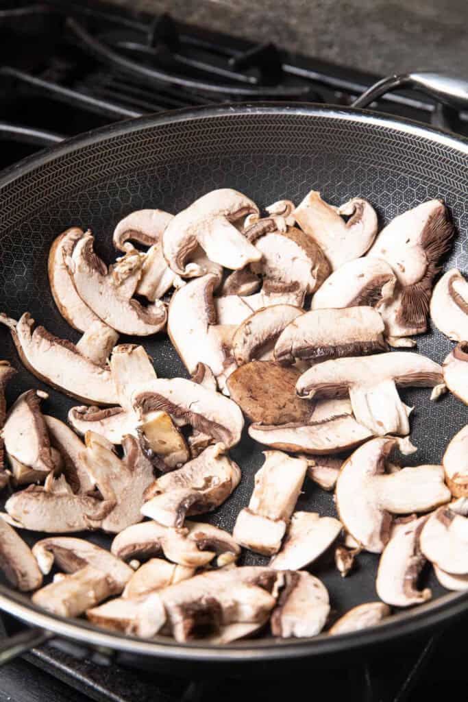 Sautéed sliced mushrooms in a pan. 