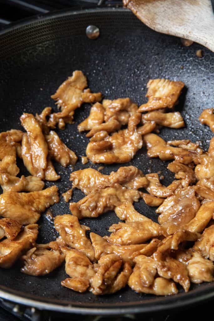 Sautéed brown chicken pieces in a wok. 