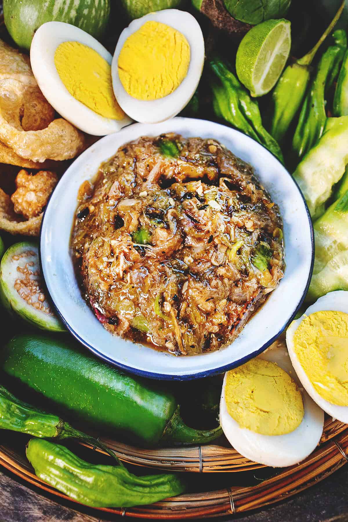 Nam Prik Num Dip in a small bowl, placed in the center of a tray with garnishes.