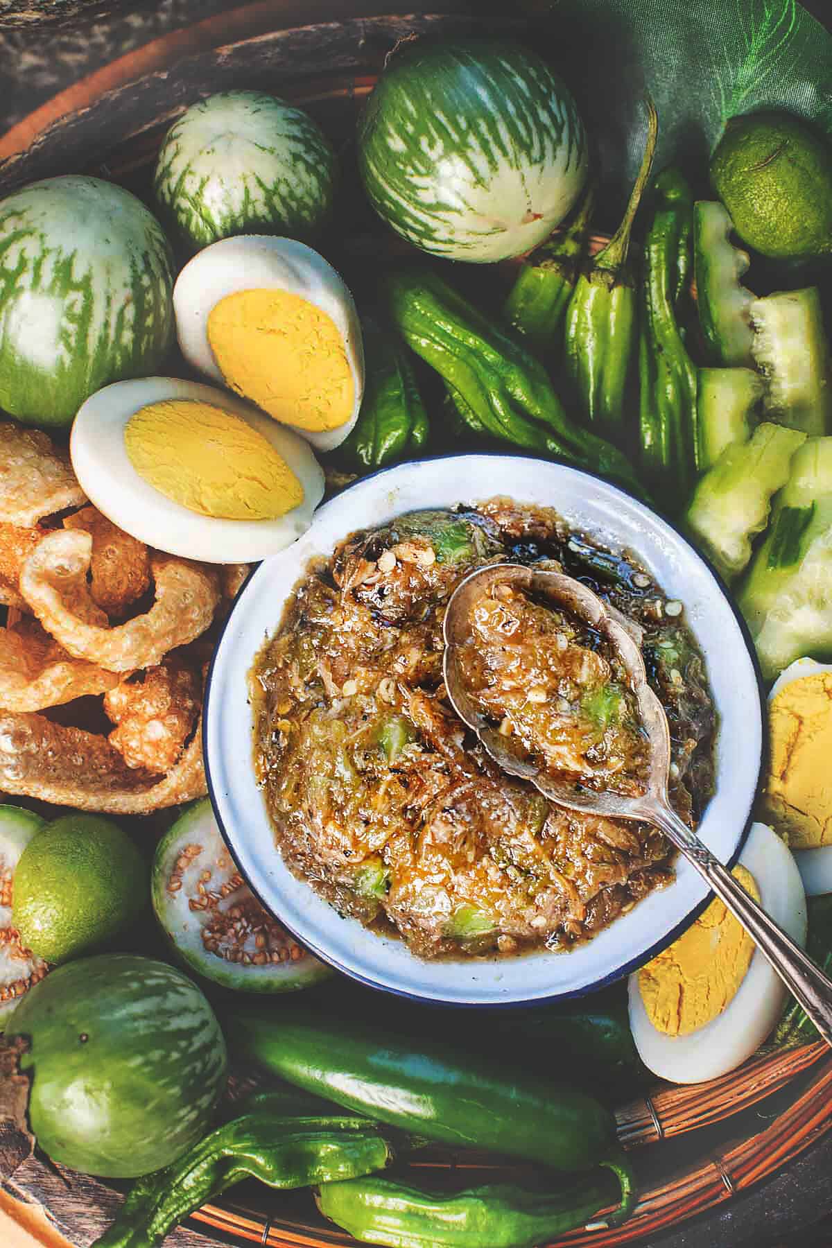 Nam Prik Noom Dip in a small bowl, with a spoon, placed in the center of a tray with garnishes.