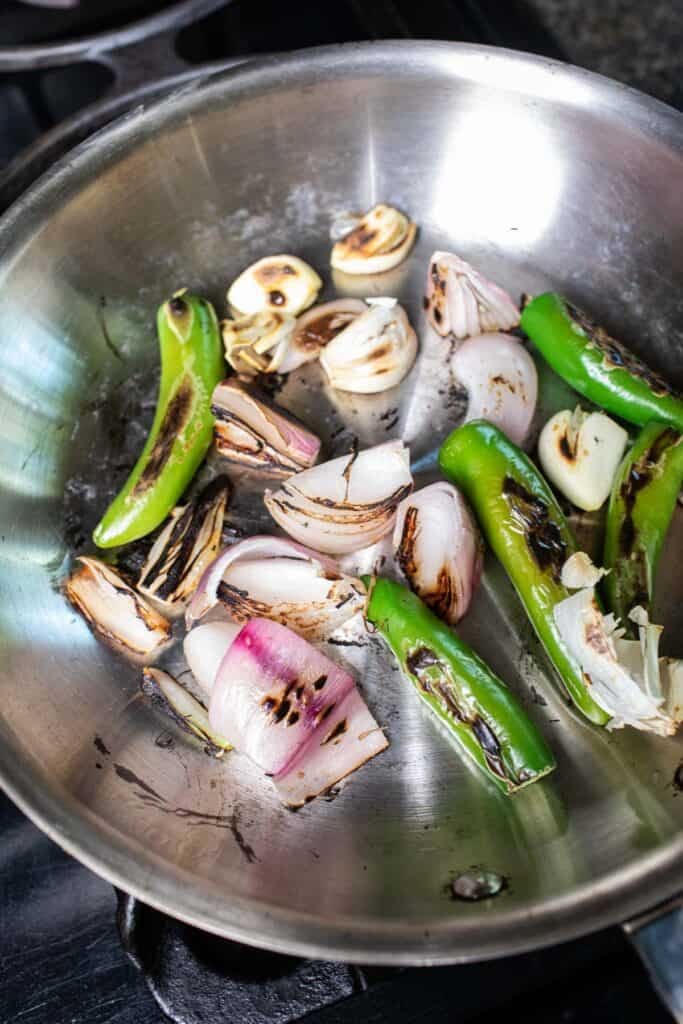 Dry roasting green pepper, garlic, and shallot in a small pan on the stove.