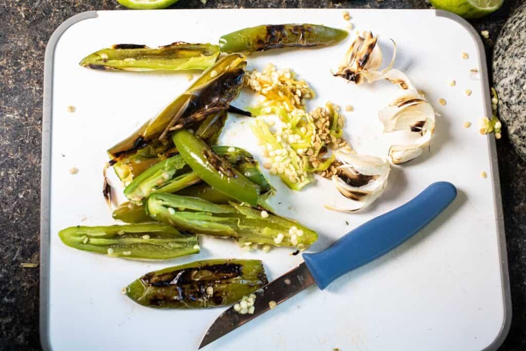 Roasted peppers with a knife for slicing with pepper seeds on the blade.