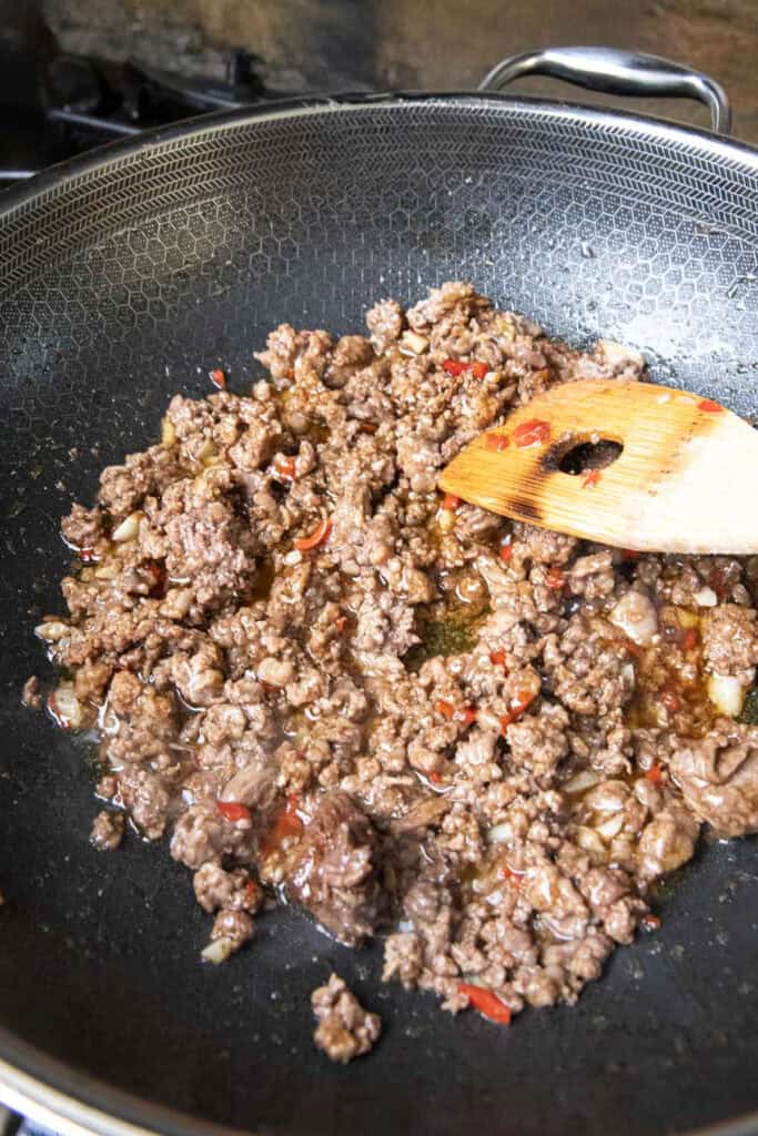 Ground beef with fried chopped Garlic and peppers in oil in a wok.