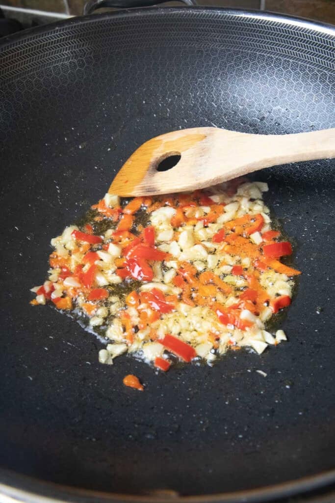 Fried chopped Garlic and peppers in oil in a wok.