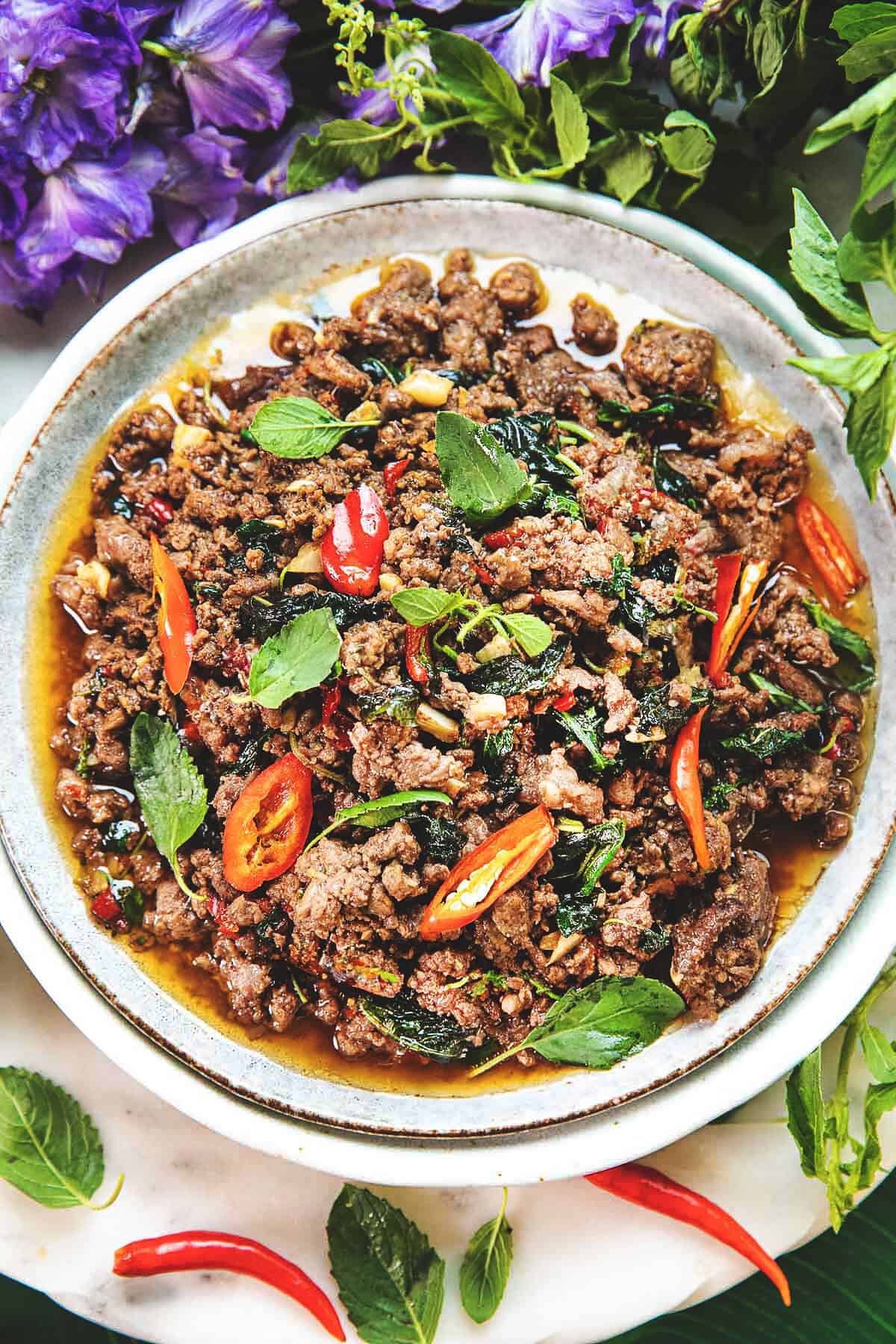 beef Pad Kra Pao stir fry in on a plate with basil leaves garnish. 