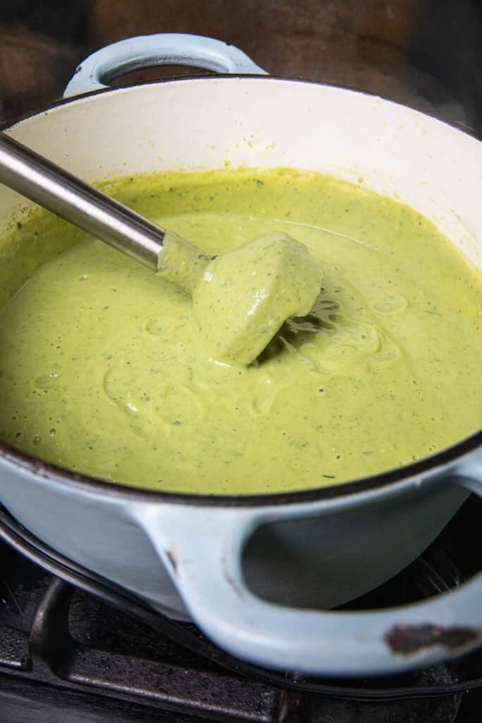 immerion blender in a pot of green soup. 