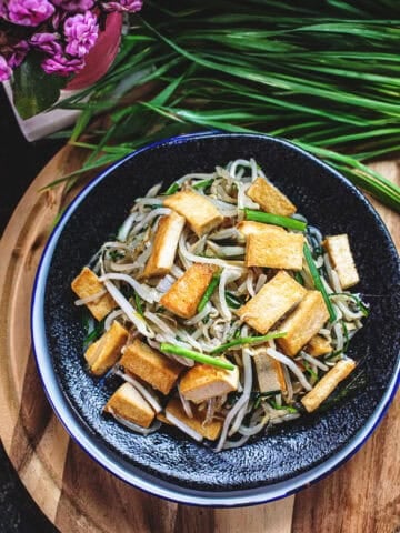 Bean sprout stir fry on a plate on a cutting board.