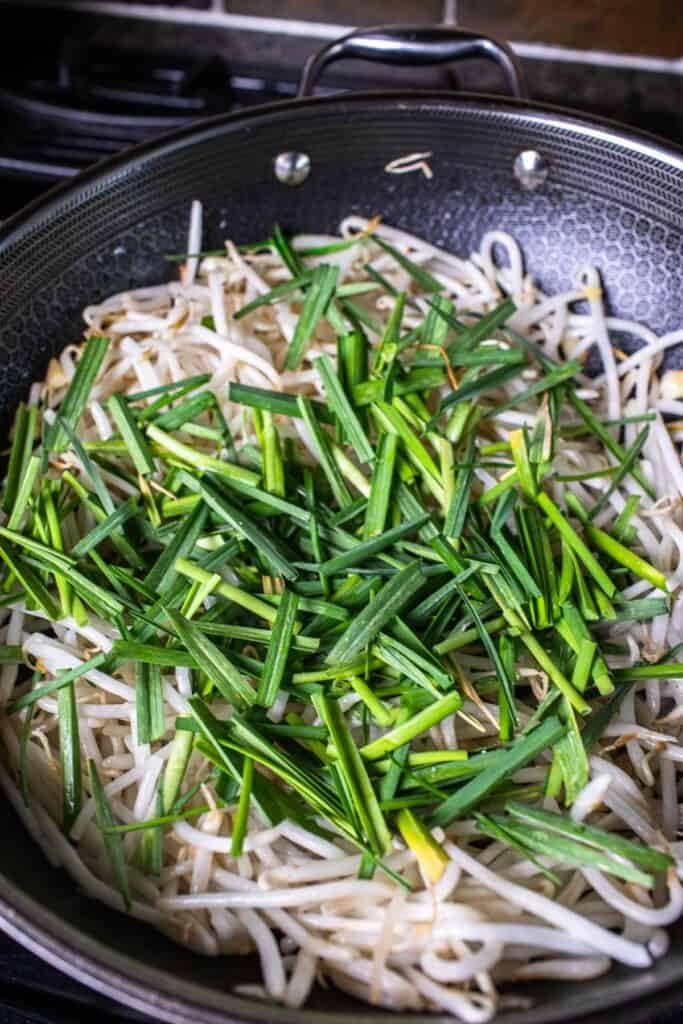 Bean sprout and chopped chives inside a wok. 