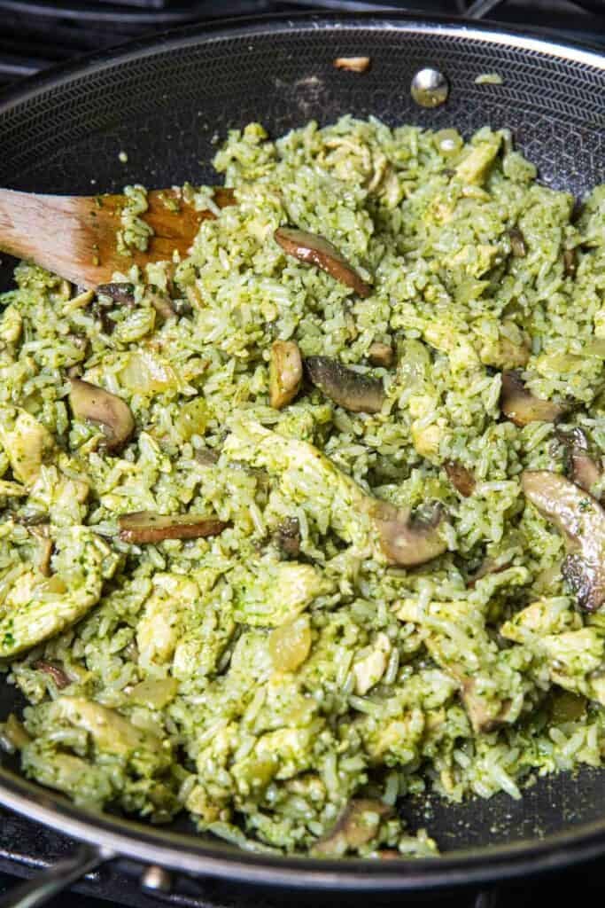 A spatula inside a wok of green chicken pesto fried rice.