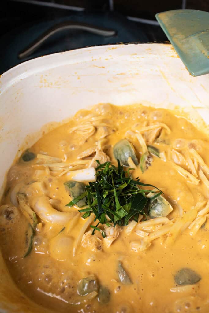 Sliced kaffir lime leaves in a bowl over Thai eggplant curry.