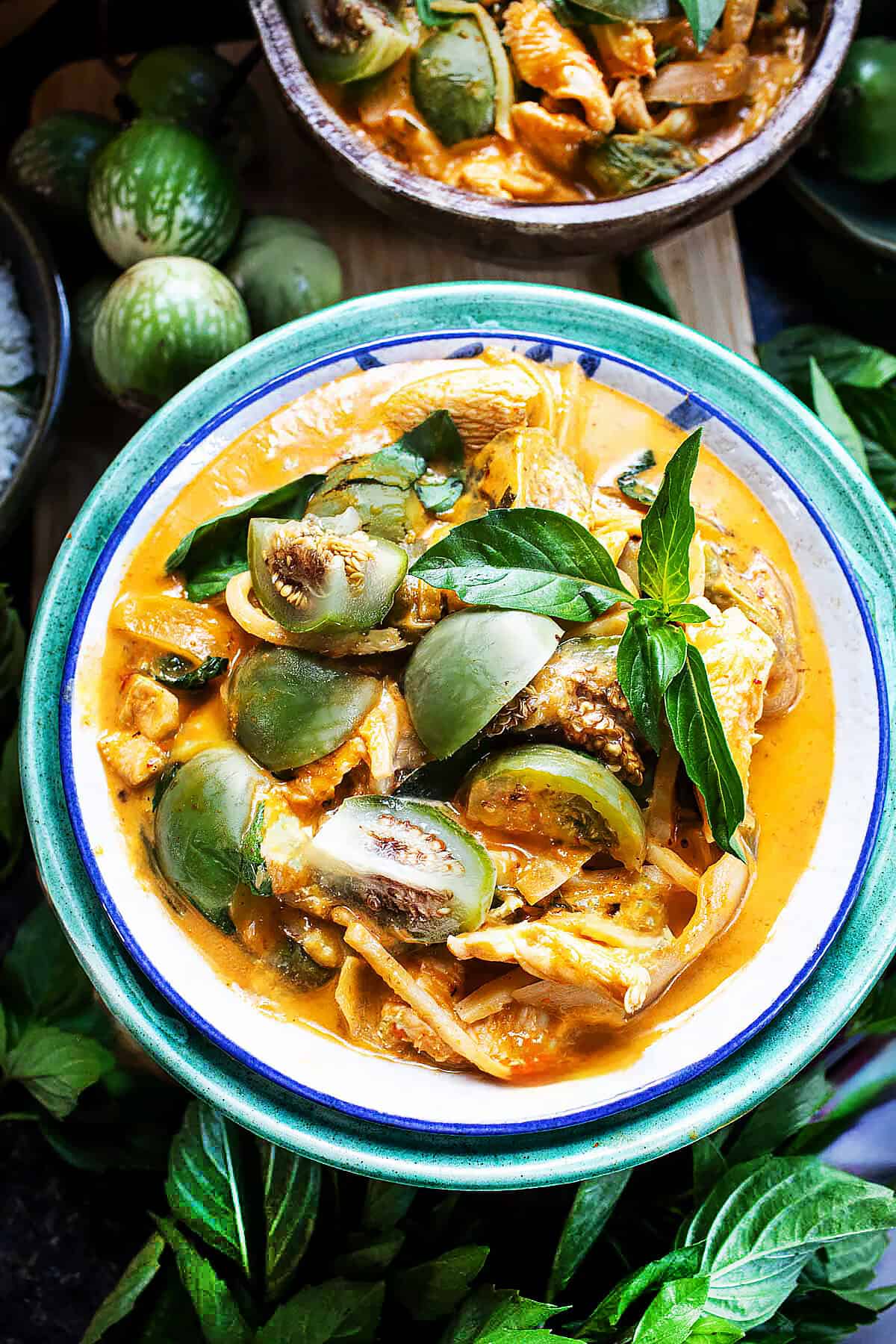 Thai eggplant curry in a bowl with Thai basil garnish on a table.