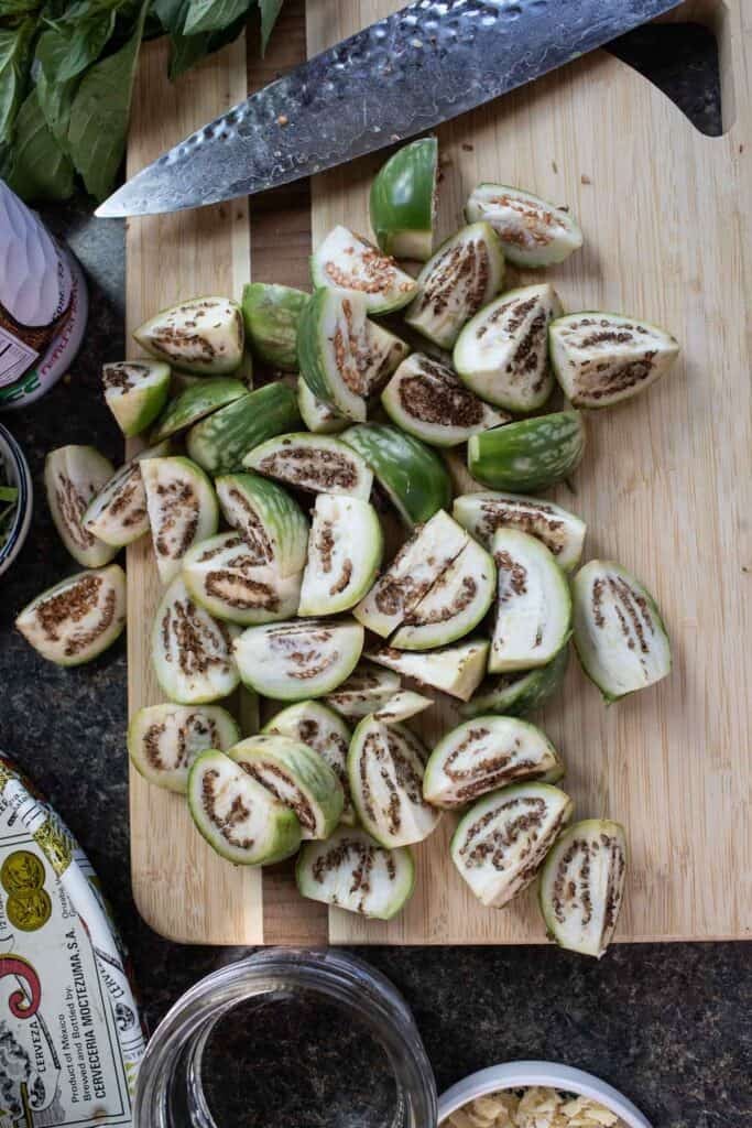 Sliced Thai eggplants over a cutting board.