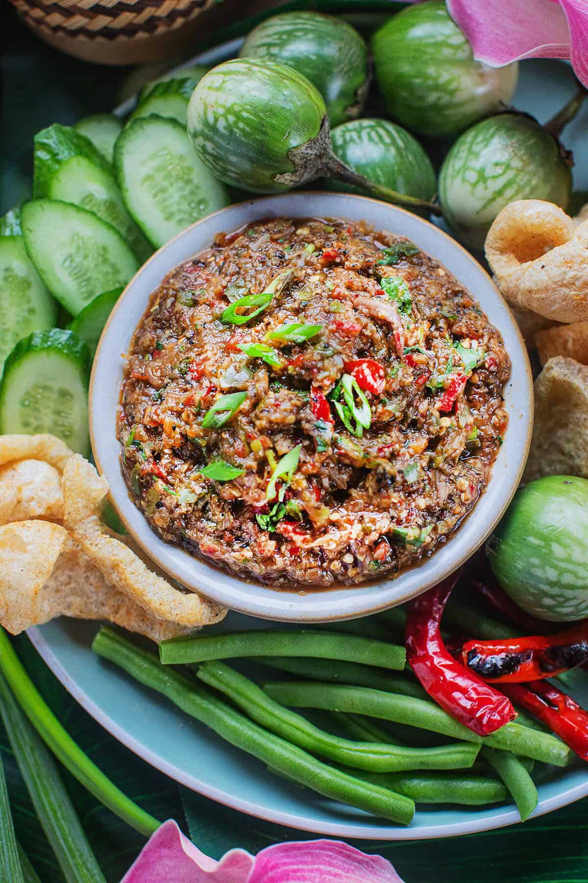 Thai roasted eggplant dip in a small bowl, surrounded by vegetables. 