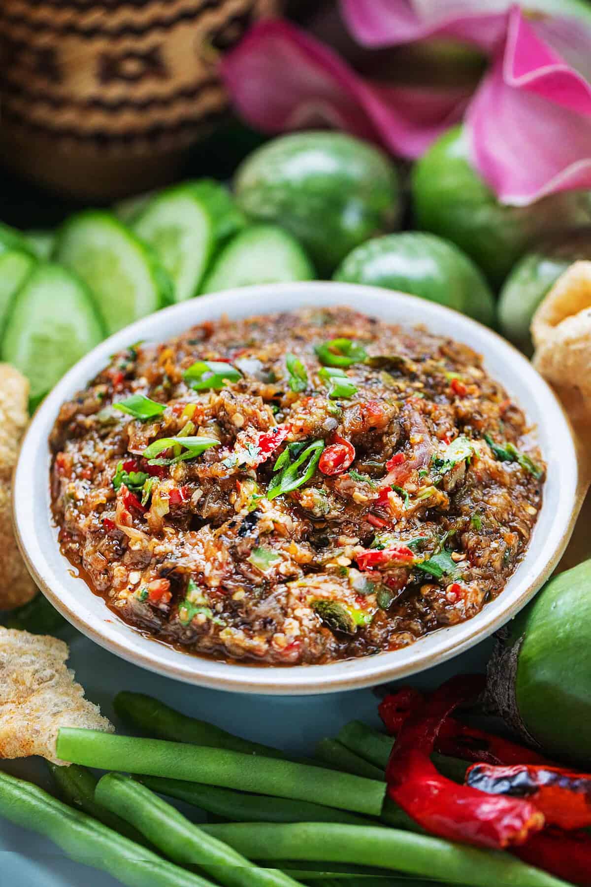 Thai roasted eggplant rib in a small bowl with veggies on the side. 