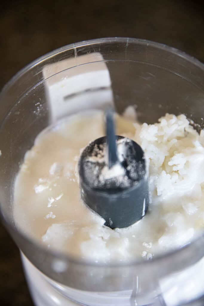 coconut milk and cooked rice inside a blender for kanom krok mixture.