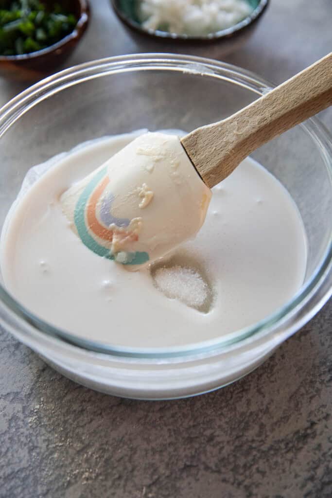 A spatula inside coconut mixture for thai coconut pancakes.
