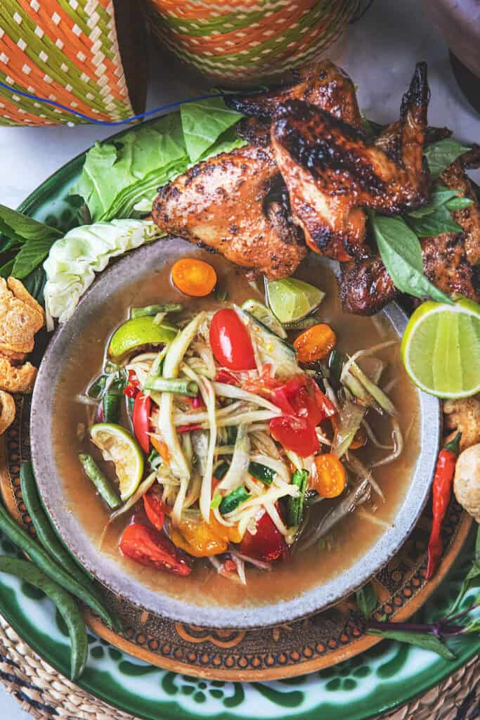 A plate of som tum or Thai papaya salad with grilled chicken on the side.
