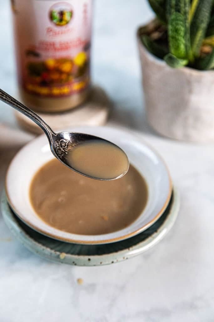 Plara fermented fish sauce for Som Tum thai papaya salad in a bowl and a spoon lifting it.