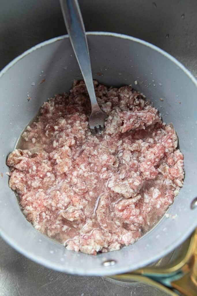 Ground pork in a pot with water.