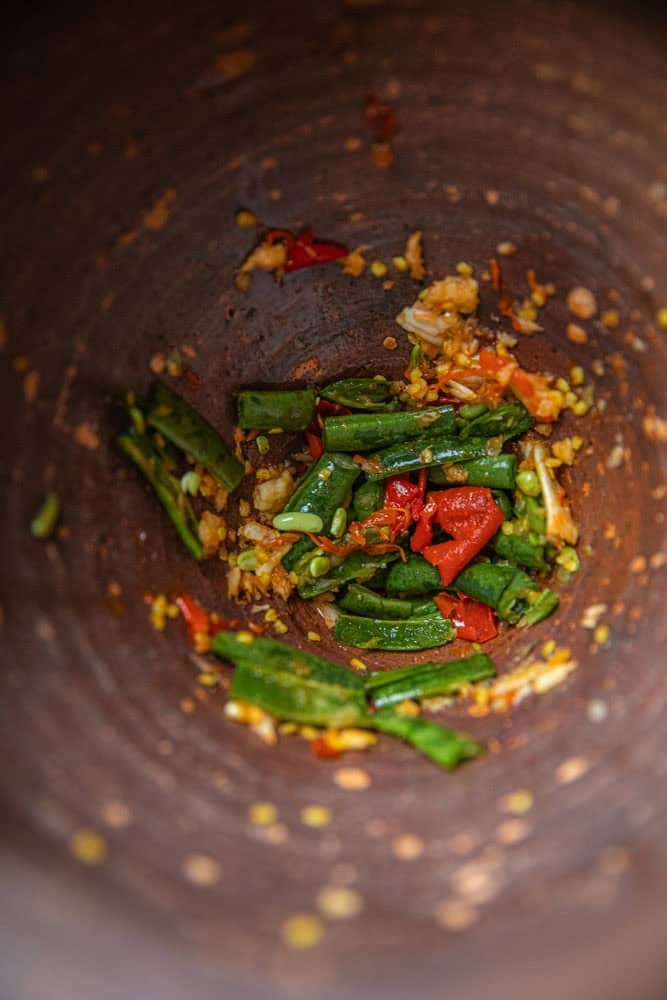 lightly crushed garlic, chilis and green beans in a mortar.