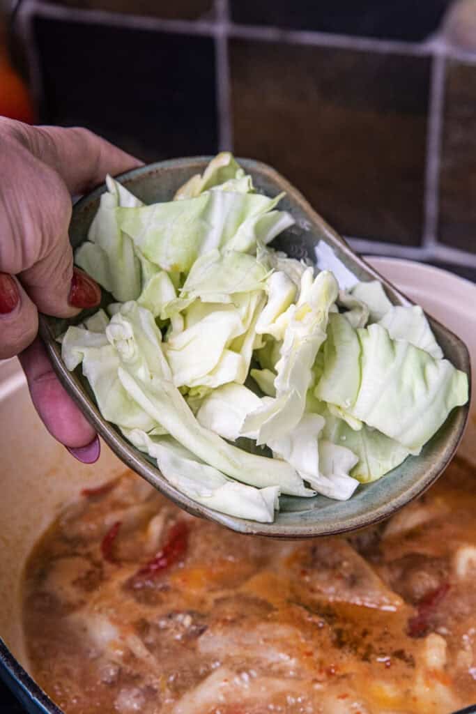 Adding sliced cabbage to Gaeng Om Gai during cooking for natural sweetness and body