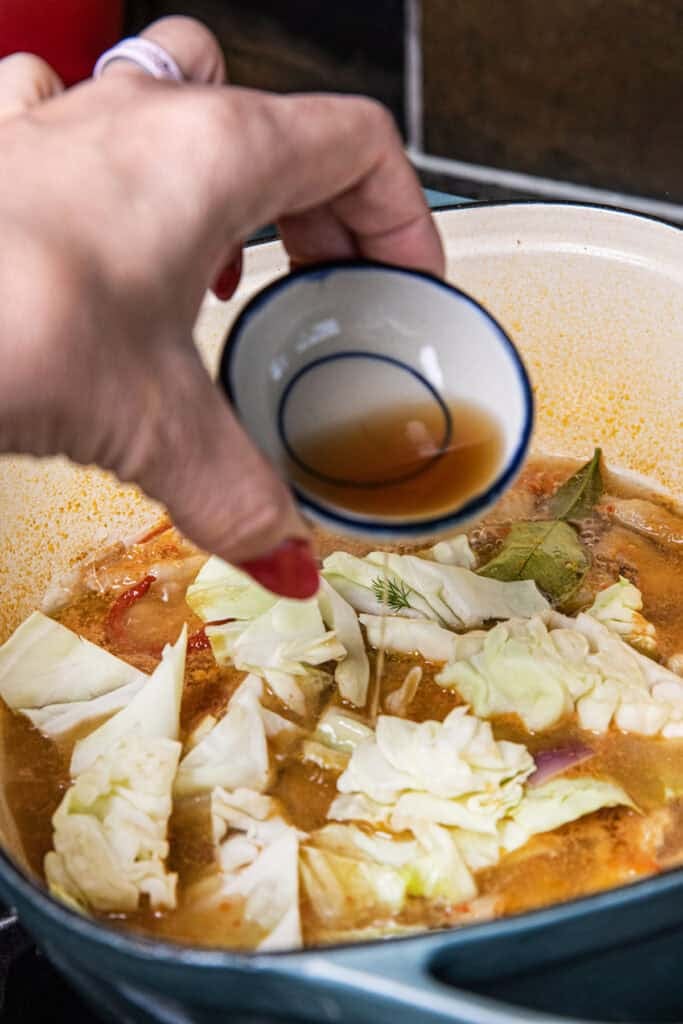 Adding fish sauce to Gaeng Om Gai for authentic Isaan flavor.