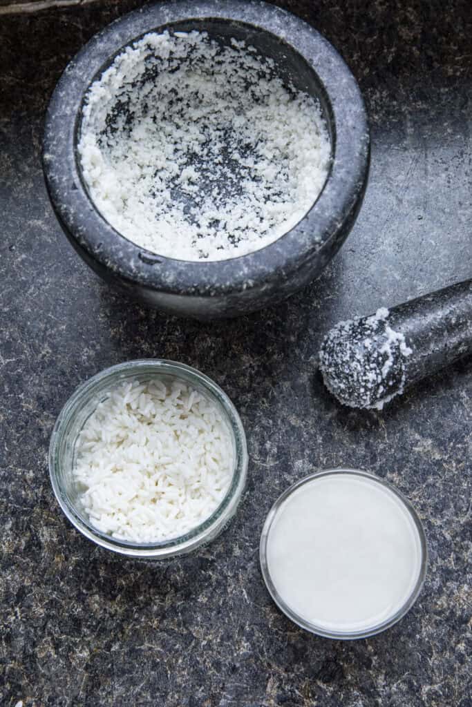 Sticky rice paste in a stone mortar and in small bowls on a counter.