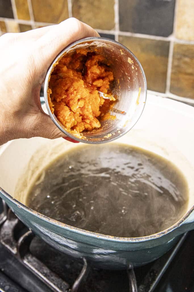 Chili paste for Gaeng Nor Mai pouring into a pot of bai ya nang juice.