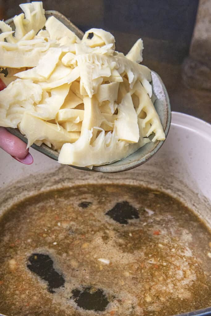 Sliced bamboo shoot tips pouring in to a pot of gaeng nor mai soup.