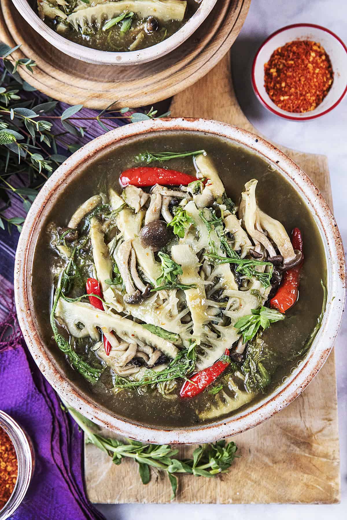 Gaeng Nor Mai soup in a bowl on a cutting board. 