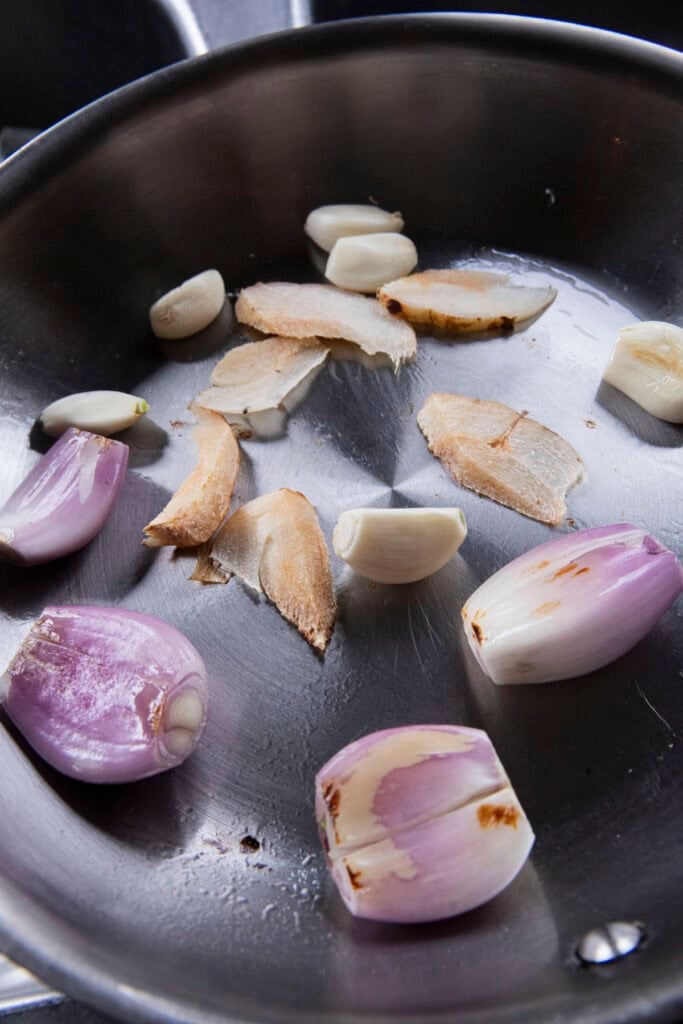 Dry-toasting shallots, garlic, and galangal in a pan for Jeow Bong chili paste.