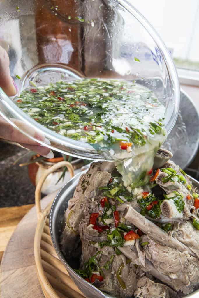Leng Saap dressing pouring over a stack of cooke pork ribs meat in a pot.