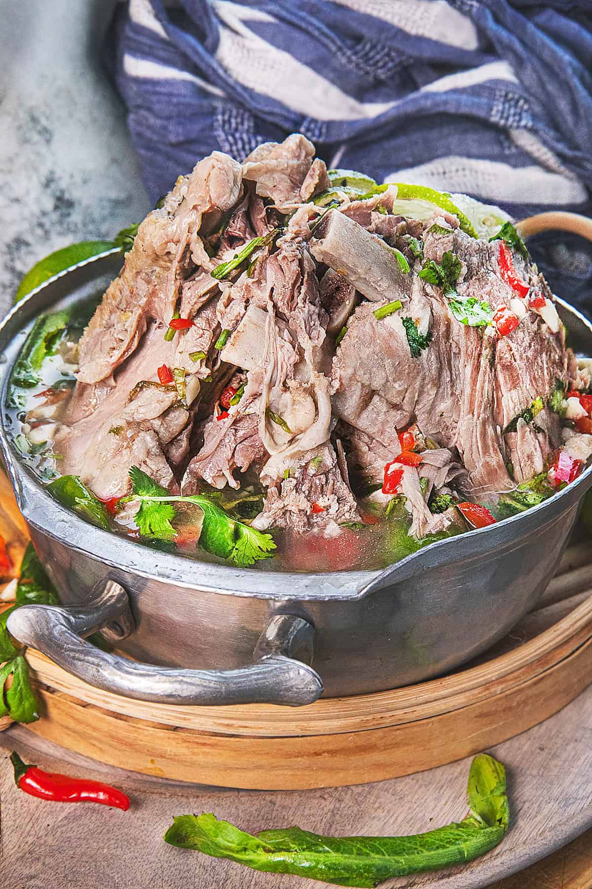 A bowl of leng Saap pork bone soup on a bowl with dressing over the meat.