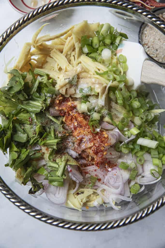 Mixing shredded bamboo shoots with herbs and seasoning for soop nor mai.