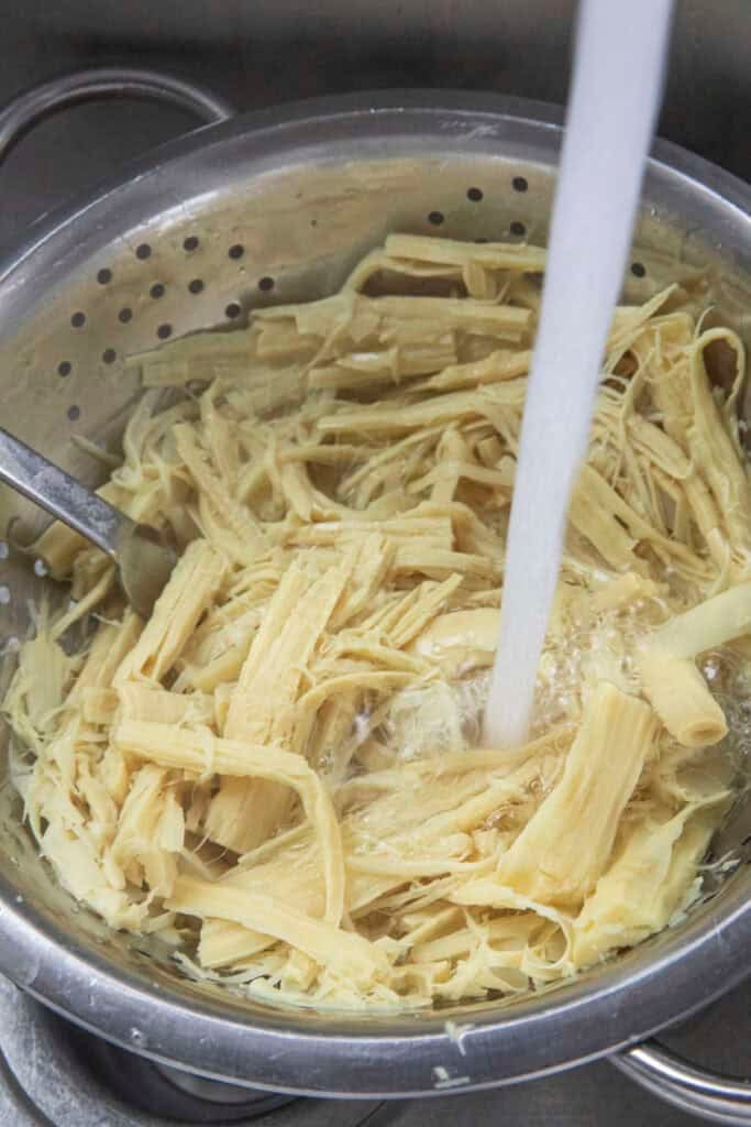 Rinsing Shredded boiled bamboo shoots prepared for Thai bamboo shoot salad.